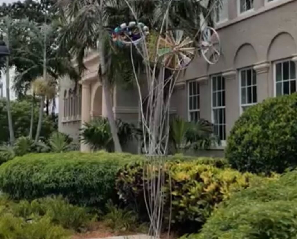 Sculpture among lush greenery and architecture.